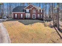 Two-story brick home with a well-manicured lawn in a wooded surrounding at 155 Matthew Way, Fayetteville, GA 30214