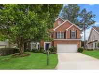 Charming brick home featuring a well-manicured front yard, mature trees, and a two-car garage at 3242 Monarch Pine Dr, Peachtree Corners, GA 30071