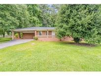 Charming one-story brick home with a well-maintained lawn and mature trees providing ample shade at 4447 Ben Hill Rd, Lithia Springs, GA 30122