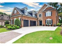 Beautiful brick home featuring a well-manicured lawn, three-car garage, and a blend of brick and stone at 1250 Atherton Park, Roswell, GA 30076
