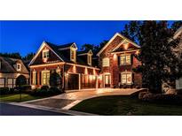 Stunning two-story brick home with a manicured lawn and a three-car garage at twilight at 1250 Atherton Park, Roswell, GA 30076