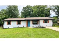Charming brick ranch-style home with a vibrant blue door and well-manicured lawn at 4074 Green Hawk Trl, Decatur, GA 30035