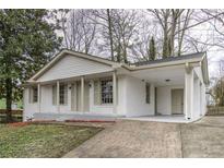 Charming, white-brick home featuring a covered carport, traditional columns, and well-maintained landscaping at 6565 Bussell Way, Riverdale, GA 30274