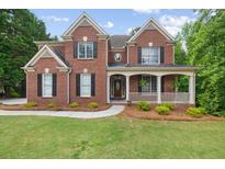 Stately brick home featuring a covered front porch and well-manicured lawn at 2525 Millwater Xing, Dacula, GA 30019