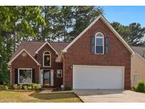 Charming brick home boasts manicured lawn and a two-car garage, framed by mature trees at 64 Harbour Lake Dr, Fayetteville, GA 30215