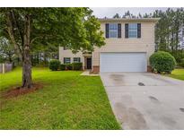 Charming two-story home featuring a two-car garage and a lush green lawn at 450 Pinevale Ct, Atlanta, GA 30349