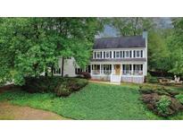 Charming two-story home featuring a welcoming front porch, white siding, black shutters and lush landscaping at 201 Tweed Ct, Sugar Hill, GA 30518