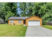 Charming single-story home featuring a front lawn, a two-car garage, and mature shade trees at 9119 Woodgreen Way, Jonesboro, GA 30238