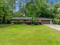 Charming ranch-style home featuring a lush green lawn, mature trees, and a two-car garage, creating great curb appeal at 1736 Morris Landers Ne Dr, Atlanta, GA 30345