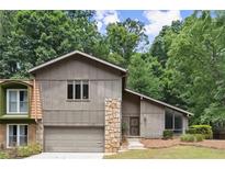 Charming home featuring a stone facade, attached garage, and lush, mature landscaping at 225 Lakeview W Rdg, Roswell, GA 30076