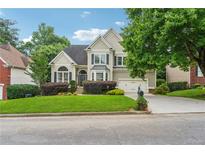 Charming two-story home with manicured lawn, mature trees, and a well-maintained front yard at 310 Arbor Creek Trl, Roswell, GA 30076