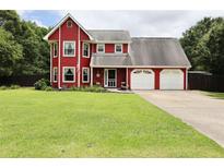 Charming two-story red home boasts an attached two car garage and a spacious front yard at 1809 Brandi Ln, Loganville, GA 30052