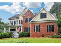 Charming two-story home featuring a brick facade, yellow siding, black shutters, and a well-manicured lawn at 1006 Amberton Ln, Powder Springs, GA 30127