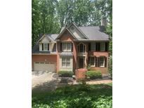 Charming brick home featuring a manicured front yard and an attached two car garage at 1915 Habersham Trce, Cumming, GA 30041