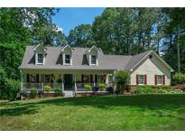 Charming single-Gathering home with a well-manicured lawn and inviting front porch nestled in a lush, wooded landscape at 2050 Lyda Ln, Loganville, GA 30052