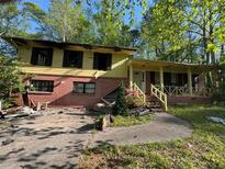 Damaged two-story home with debris strewn in the front yard needs extensive repairs and restoration at 447 Martindale Ct, Stone Mountain, GA 30088