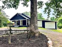 Charming blue cottage-style home with white trim, a porch with swing, and an oversized garage with carriage doors at 776 Green Dr, Canton, GA 30114