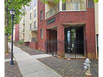 Brick exterior building entrance with black metal gated door and sidewalk with mature tree in view at 870 Mayson Turner Rd # 1207, Atlanta, GA 30314
