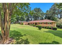 Beautifully landscaped front yard showcasing a charming brick home with manicured shrubs and mature trees at 4177 Hapsburg Ct, Decatur, GA 30034