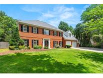 Charming two-story red brick home with manicured lawn and black shutters on a sunny day at 2903 Ashebrooke Ne Dr, Marietta, GA 30068
