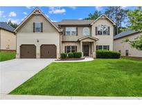 Charming two-story home featuring a well-manicured lawn, inviting facade, and two-car garage at 7946 White Oak Loop, Stonecrest, GA 30038