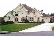 Elegant two-story brick home featuring a manicured lawn and a long driveway leading to an attached garage at 2609 Jacobs Crest Cv, Grayson, GA 30017