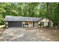 Charming single-story home with a two-car garage and a well-maintained front yard surrounded by mature trees at 225 Hardwood Dr, Covington, GA 30016