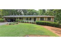 Charming single-story home featuring a well-manicured lawn, carport, and brick accents at 2600 Amberly Dr, Dunwoody, GA 30360
