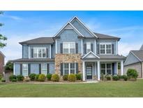 Charming two-story home featuring blue siding, stone accents, a welcoming front porch, and lush green lawn at 2953 Balvenie Pl, Acworth, GA 30101