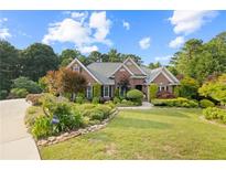 Beautifully landscaped brick home with lush lawn, mature trees, and a welcoming entrance at 1005 Cromwell Cv, Snellville, GA 30078