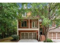 Charming brick home with a two-car garage and second story balcony surrounded by mature trees at 2005 Eagle Rdg, Roswell, GA 30076