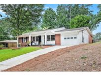 Charming brick home with a white garage, front porch, well-manicured lawn, and a long driveway at 3880 Admiral Dr, Chamblee, GA 30341