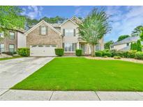 Charming two-story home featuring a manicured lawn, brick facade, and attached two-car garage at 3060 Mccannon Mill Dr, Dacula, GA 30019