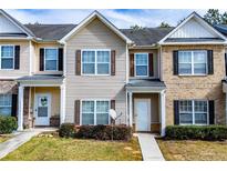Two-story townhouse featuring neutral siding, charming shutters, and a well-maintained front yard at 2326 Bigwood Trl, Atlanta, GA 30349