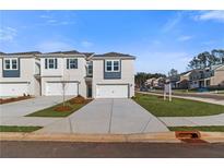 Newly constructed townhomes featuring attached garages and modern architectural details stand on manicured lawns at 329 Heavenly Hollow Pl, Mcdonough, GA 30253
