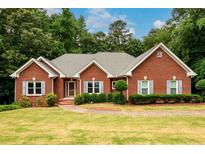Charming brick home with a well-manicured lawn, beautiful landscaping, and classic gray shutters at 3648 Clark Hill Way, Buford, GA 30519