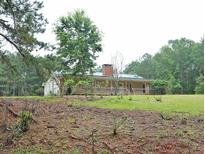 Ranch-style home on a grassy lot with a brick chimney and covered porch at 3129 Etchison Rd, Loganville, GA 30052