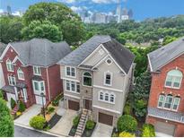 Beautiful home exterior featuring stone accents, a two-car garage, and a view of the Atlanta skyline at 13 Highland Park Ne Ln, Atlanta, GA 30306