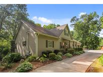 Charming home featuring manicured landscaping, a cozy front porch, and long driveway nestled among mature trees at 265 Shane Dr, Canton, GA 30115