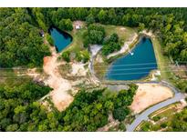 Expansive aerial view of property featuring mature trees, two ponds and unpaved access roads at 300 Old Boy Scout Rd, Whitesburg, GA 30185