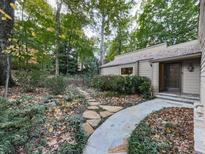 Charming home with a stone walkway leading to the front door, surrounded by lush landscaping and mature trees at 3771 Club Nw Dr, Kennesaw, GA 30144
