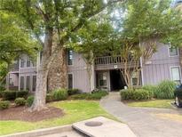 Inviting condo exterior featuring mature trees, lush landscaping, and a charming walkway to the front door at 3915 Woodridge Way, Tucker, GA 30084