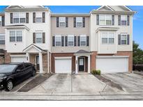 Attractive townhome with neutral siding, dark shutters, brick accents, a single-car garage, and concrete driveway at 931 Society Cir, Atlanta, GA 30331