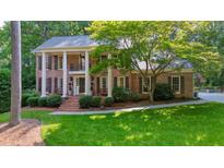 Beautiful brick home featuring a covered porch and well-manicured lawn at 11940 Mountain Laurel Dr, Roswell, GA 30075