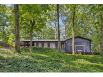 Charming home featuring dark blue painted brick and siding, lush landscaping, and a porch swing at 6878 Brandon Mill Rd, Sandy Springs, GA 30328
