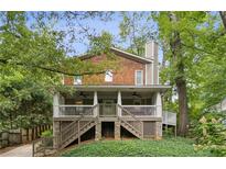 Charming two-story home featuring a spacious covered porch, shingle siding, and lush greenery all around at 443 Lakeshore Ne Dr, Atlanta, GA 30307