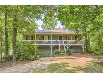Charming home featuring a spacious front porch and landscaped front yard surrounded by mature trees at 62 Sweetwater Pkwy, Powder Springs, GA 30127