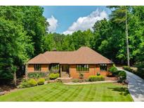 Brick home with well-manicured lawn and mature trees, offering a serene and inviting curb appeal at 1385 Northcliff Trce, Roswell, GA 30076