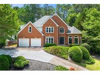 Charming two-story brick home featuring a well-manicured front yard and a two-car garage at 542 Fairway Dr, Woodstock, GA 30189