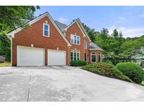 Charming two-story brick home featuring an attached two-car garage and well-manicured landscaping at 542 Fairway Dr, Woodstock, GA 30189